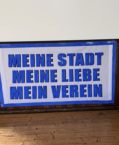 Schild mit dem Text „MEINE STADT MEINE LIEBE MEIN VEREIN“ in blauer Schrift.