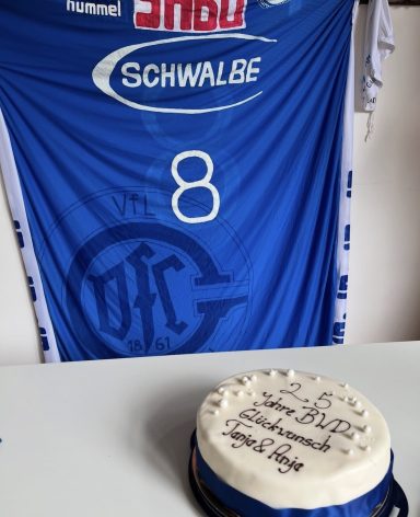 Ein Kuchen mit einer blauen Dekoration und einer Aufschrift in der Nähe eines blauen Trikots.